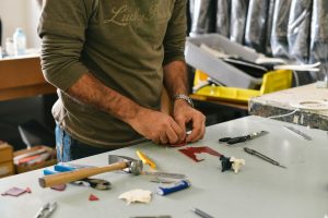 A technician's hands and tools laid out on a workbench