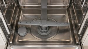 The inside of an empty dishwasher tub seen from above with the lower spray arm in place